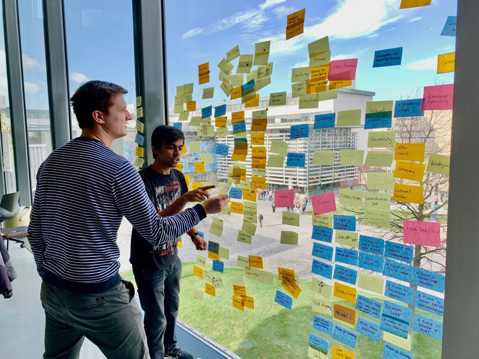 Two people mapping ideas with sticky notes on a window
